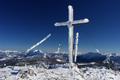 Das stark umwindete Gipfelkreuz am Hirzberg mit Ausblick zum Grimming (links) und Kammspitz (rechts).